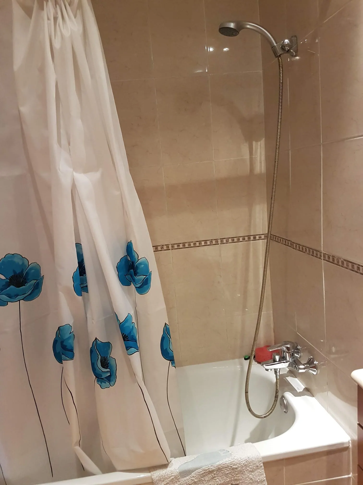 Estado previo de la zona de bañera, con revestimiento cerámico beige y objetos de uso diario