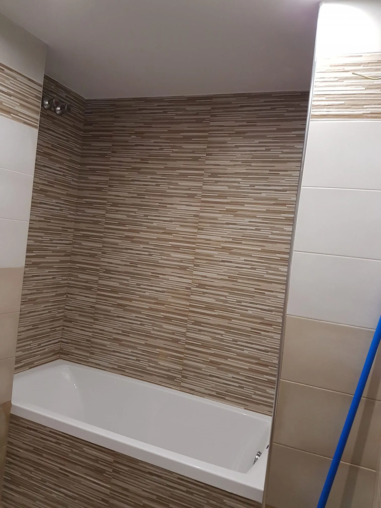 Zona de bañera con el revestimiento cerámico colocado y la grifería todavía pendiente